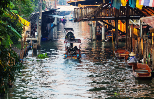 Pirogue traditionnelle transportant des touristes le long d'un marché flottant en Thaïlande.