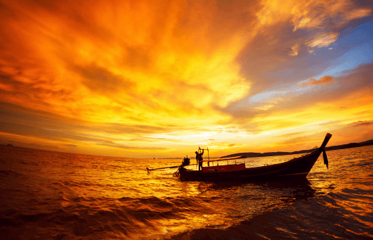 couche de soleil sur la mer de la thailande avec bateau traditionnel