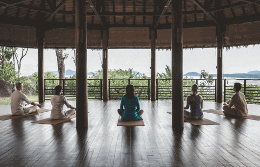 Groupe pratiquant le yoga en Thailande en plein air en sous un pavillon thailandais
