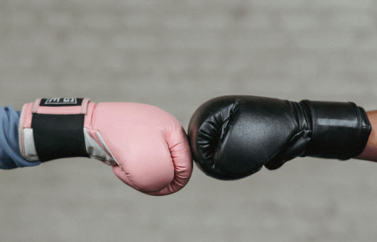 Gants de boxe thailandaise Muay Thai colores portes par deux combattants faisant face l'un à l'autre